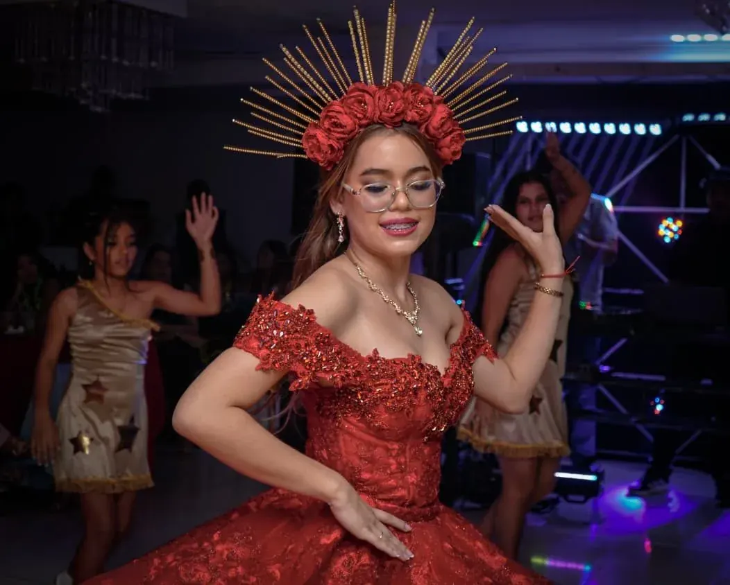 Quinceañera con vestido rojo bailando durante su celebración